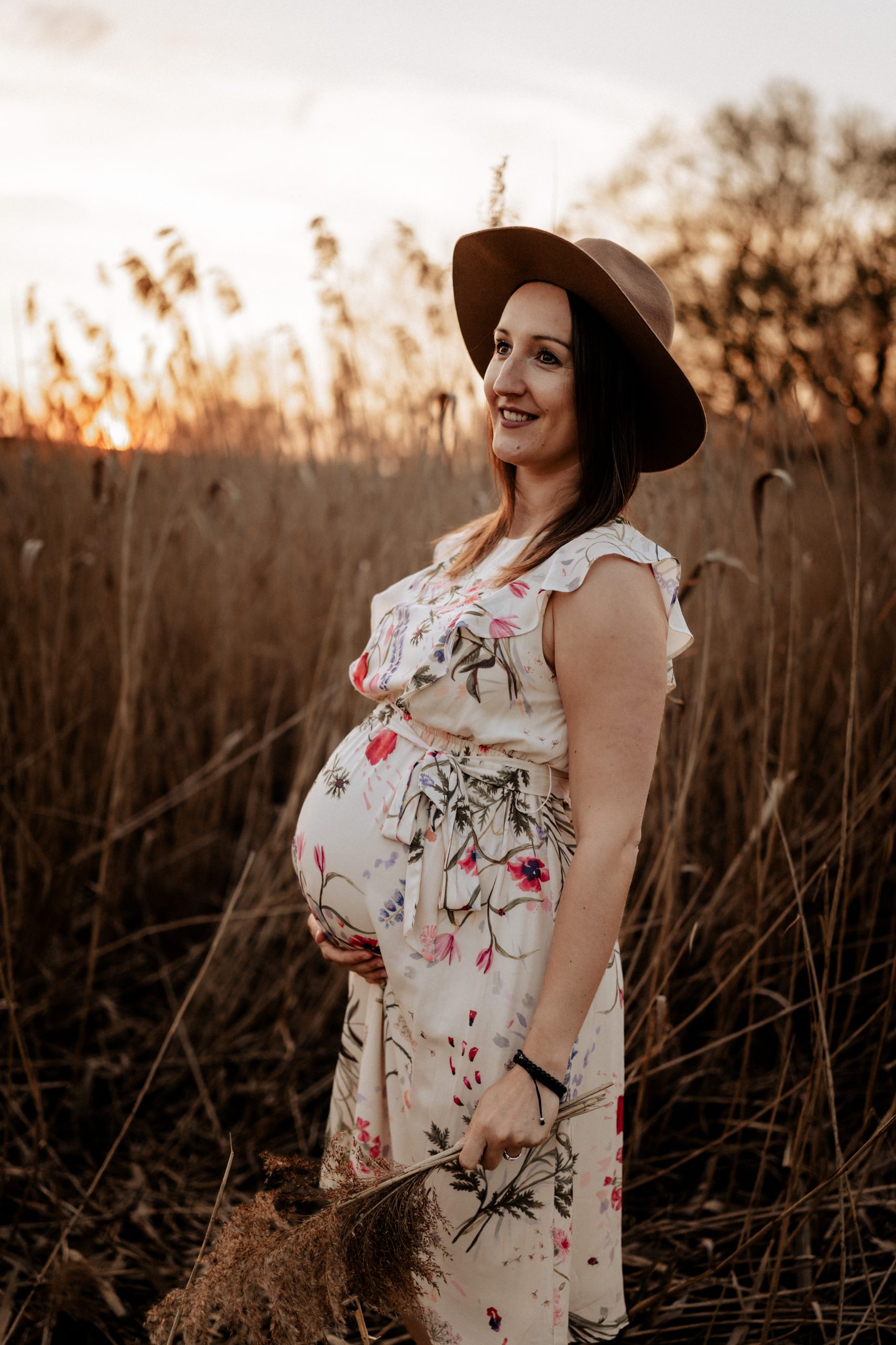 fotograf fotografiert schwangere Frau im Schilffeld