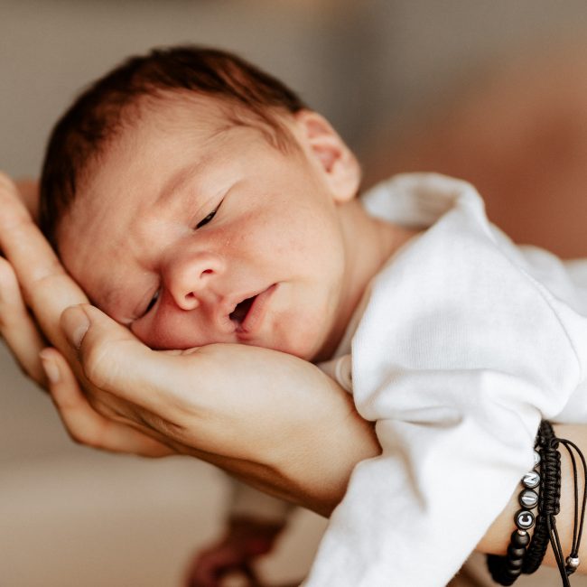 fotograf fotografiert Baby schlafend in den Armen der Mama