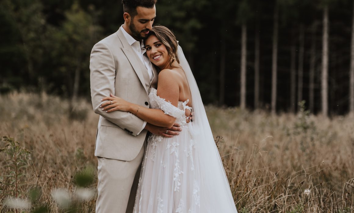 fotograf fotografiert paar anschmiegend im Gras bei After wedding shooting