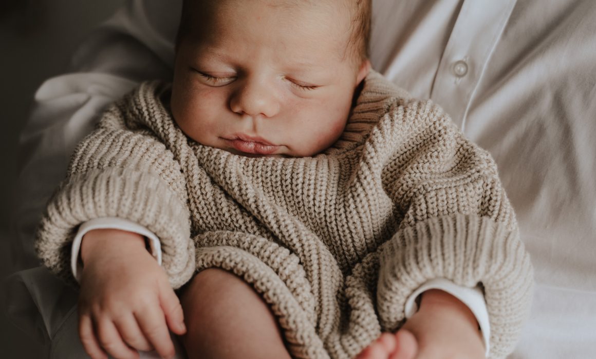 fotograf fotografiert baby schlafend in den armen des Papas eingekuschelt